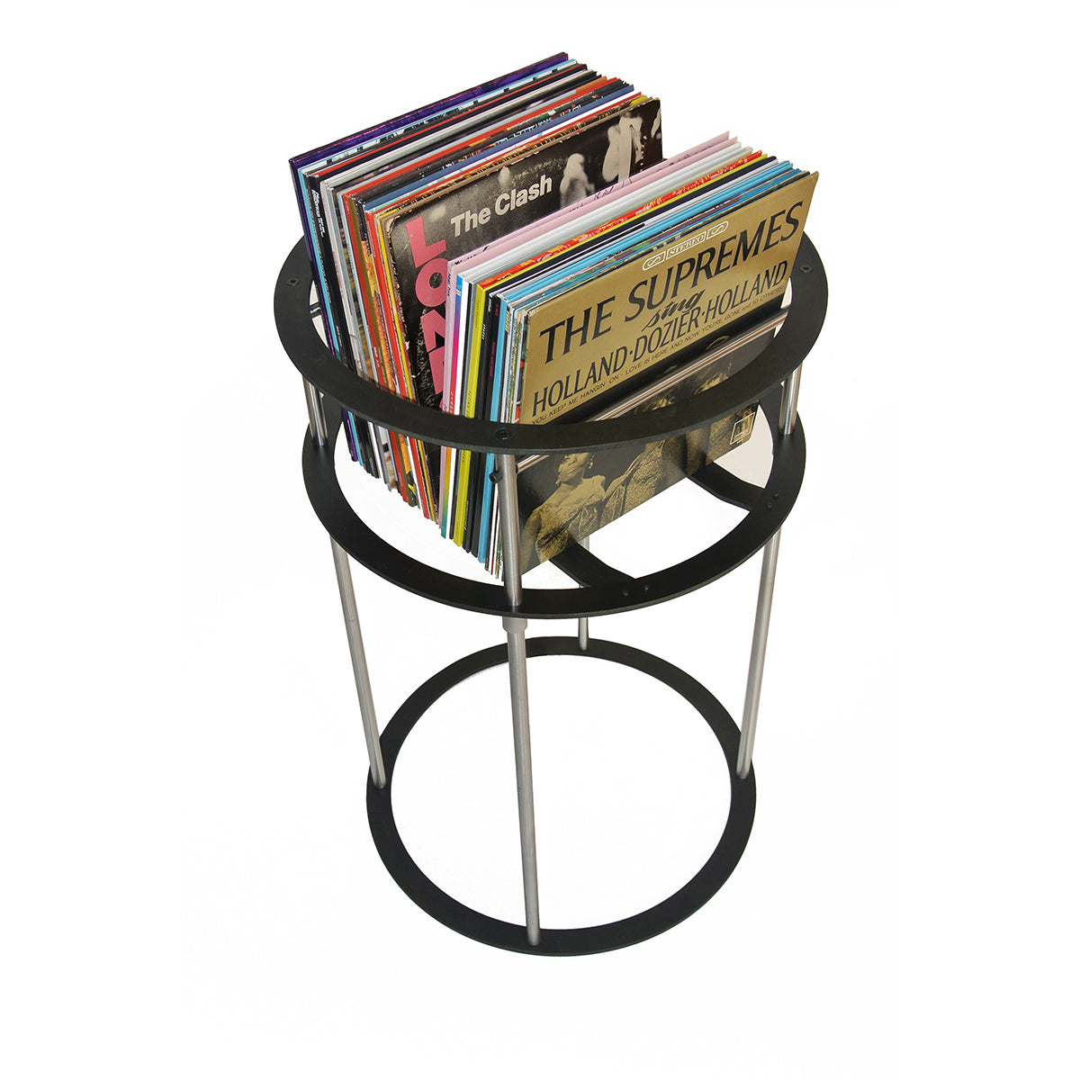 Two record album covers visible in a stack of vinyl records on a metal stand