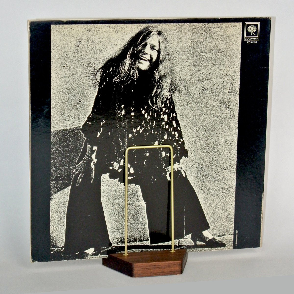 Back view of a coardboard album cover proped on a small wood and brass stand